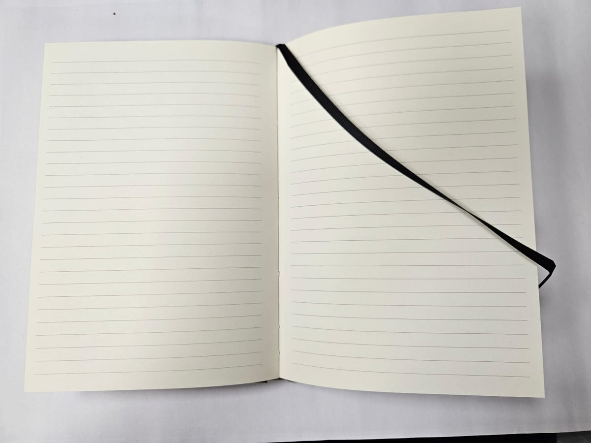 An open lined notebook with cream-colored pages and a black ribbon bookmark, photographed from above on a light gray background.