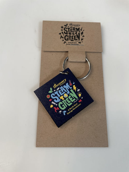 Keychain with colourful text on a navy background, displayed on a brown card with Steam 2 Green logo.