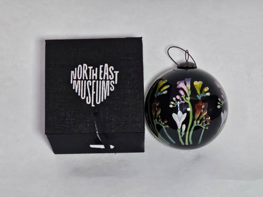 Black ornament with floral design next to a black box labeled 'North East Museums' on a light gray background