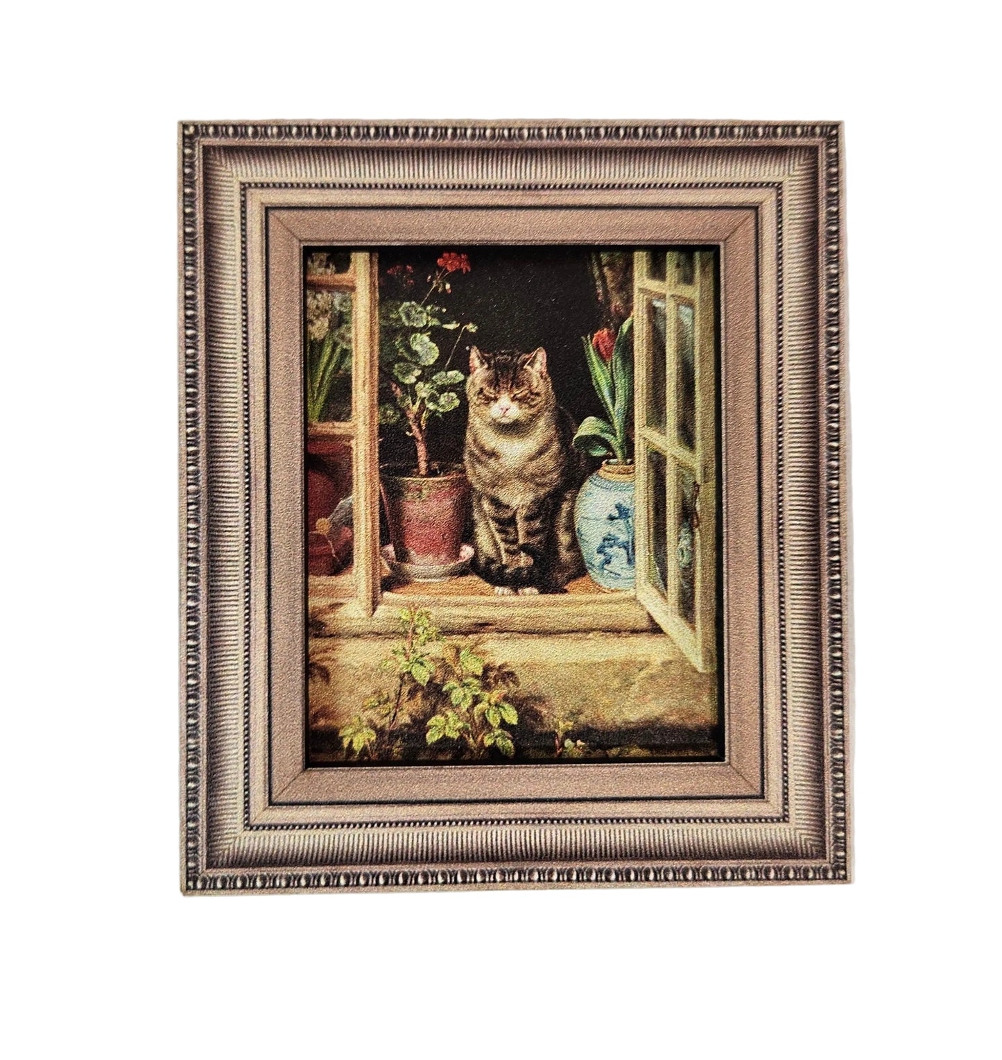 A framed art print depicting a fluffy brown tabby cat sitting on a windowsill with potted plants, set in an ornate textured silver and gold frame against a light wall.