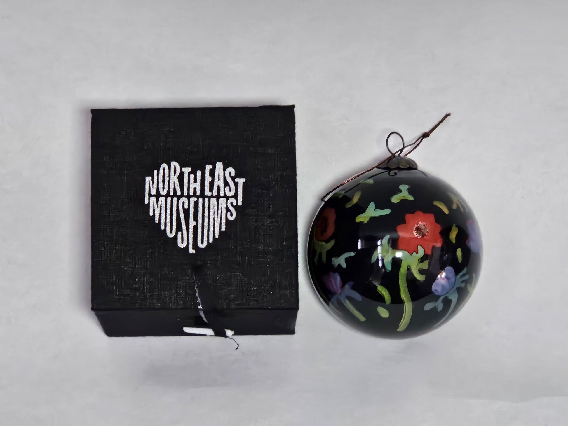 Decorative ornament with floral patterns next to a black box labeled 'North East Museums' on a light gray background
