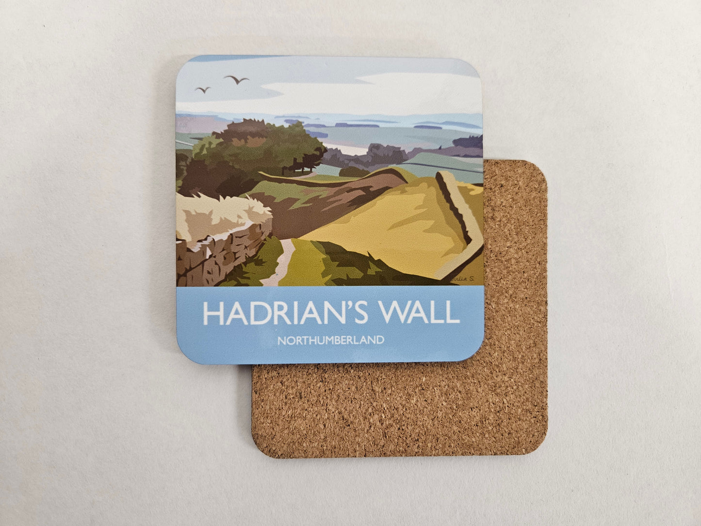 A colourful image of countryside and distinctive Roman wall going through it with the title HADRIAN'S WALL, NORTHUMBERLAND on a blue back ground at the bottom the image. 